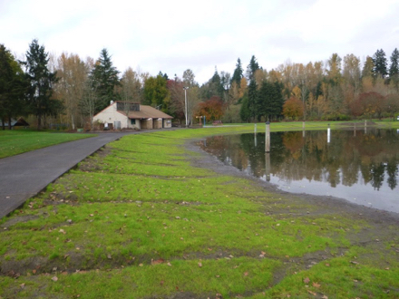 Hard surface path at pond – grass between path and pond – gravel – restroom – roped off for swimming in summer